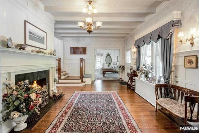 sitting room with beamed ceiling, hardwood / wood-style flooring, and an inviting chandelier