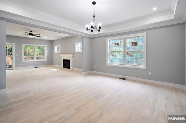 unfurnished living room with a tray ceiling, ornamental molding, ceiling fan with notable chandelier, and light wood-type flooring