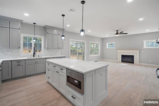 kitchen with backsplash, ceiling fan, built in microwave, sink, and gray cabinets