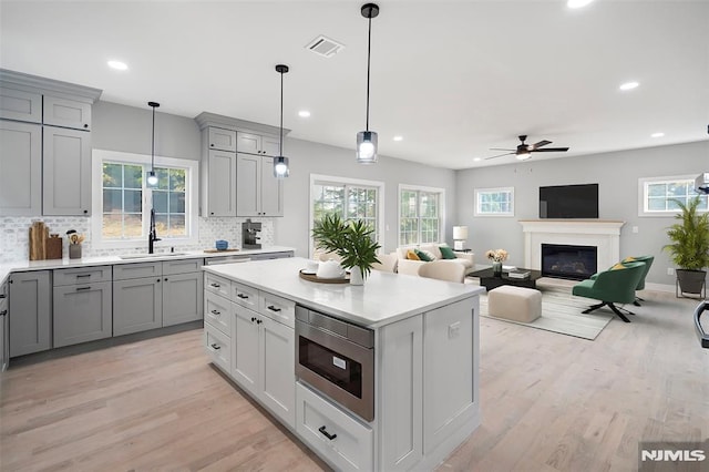 kitchen with backsplash, ceiling fan, built in microwave, sink, and gray cabinets