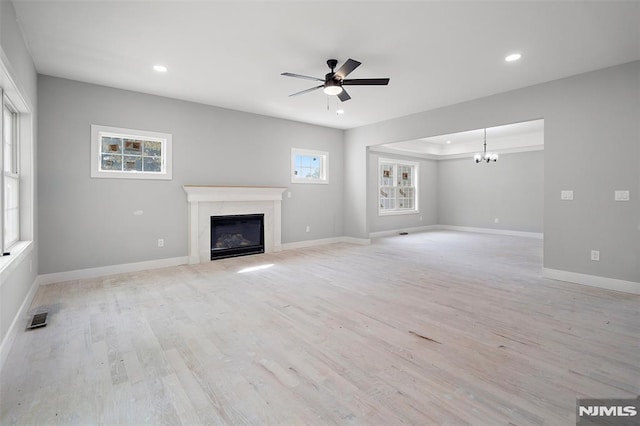 unfurnished living room featuring light hardwood / wood-style floors and ceiling fan with notable chandelier