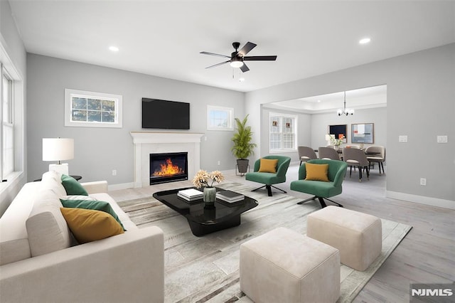 living room with ceiling fan with notable chandelier and light hardwood / wood-style floors