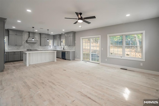 kitchen with stainless steel dishwasher, custom range hood, gray cabinets, a kitchen island, and hanging light fixtures