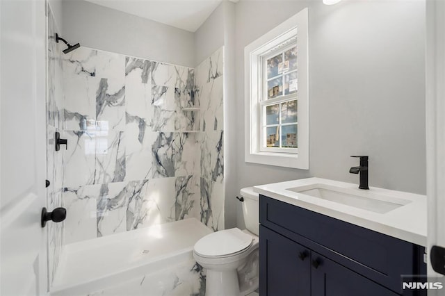 bathroom featuring toilet, a shower, and vanity