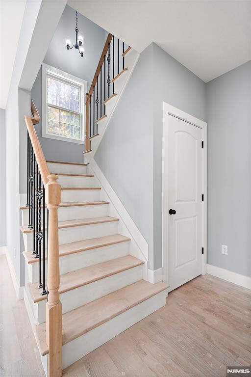 staircase with hardwood / wood-style floors and a chandelier