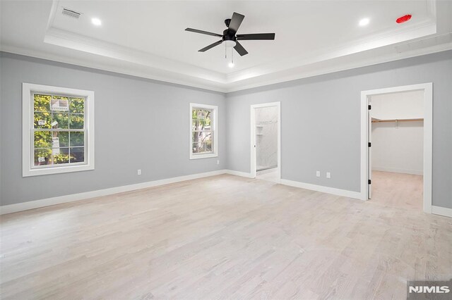 unfurnished room featuring ceiling fan, light hardwood / wood-style floors, crown molding, and a tray ceiling