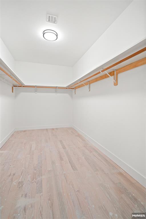 walk in closet with light hardwood / wood-style floors