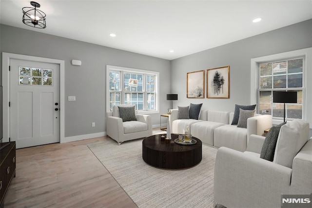 living room with a chandelier, a healthy amount of sunlight, and light hardwood / wood-style flooring