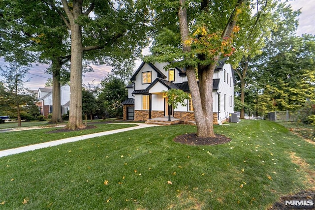 view of front of property with central AC and a front lawn