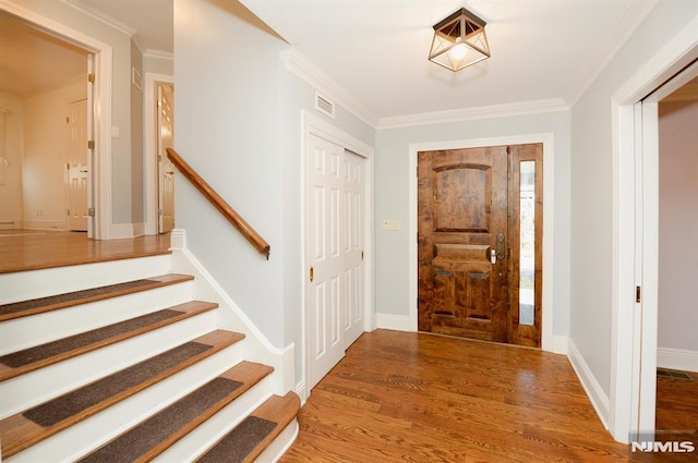 foyer entrance with wood-type flooring and ornamental molding