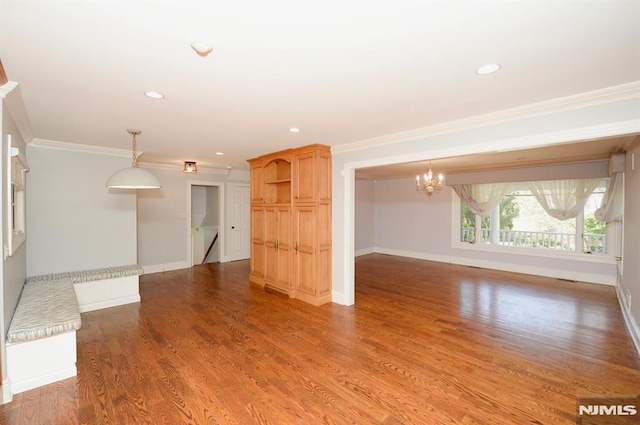 unfurnished living room with an inviting chandelier, hardwood / wood-style flooring, and crown molding