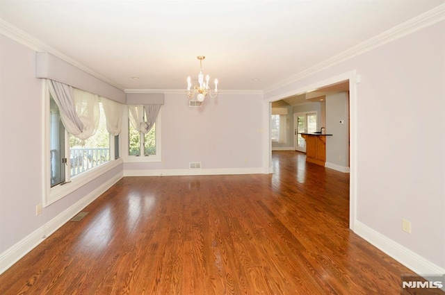 spare room with ornamental molding, an inviting chandelier, and hardwood / wood-style floors