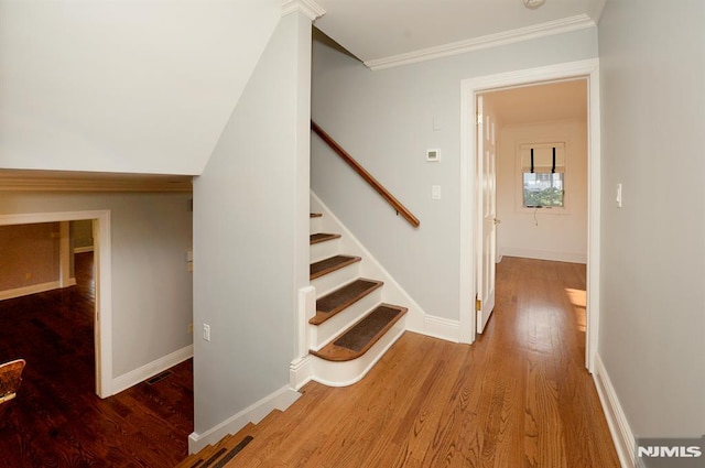 stairs with crown molding and hardwood / wood-style floors