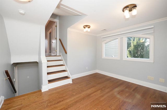 stairway featuring crown molding and hardwood / wood-style flooring