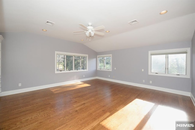 empty room with vaulted ceiling, hardwood / wood-style flooring, ceiling fan, and a healthy amount of sunlight