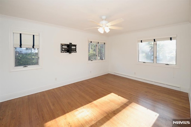 spare room featuring ceiling fan, a wealth of natural light, hardwood / wood-style flooring, and a baseboard heating unit