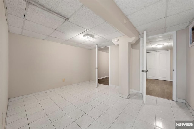 basement with a paneled ceiling and light tile patterned flooring