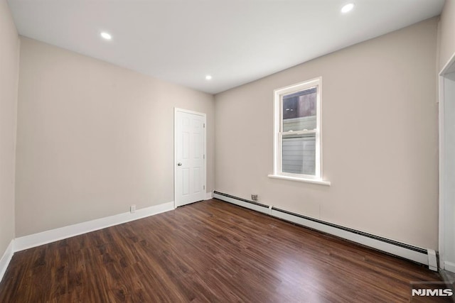 spare room featuring dark wood-type flooring and a baseboard heating unit