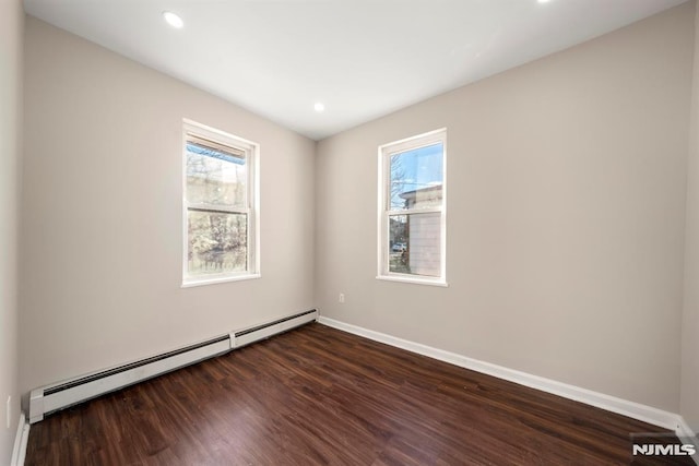 unfurnished room featuring dark hardwood / wood-style flooring and baseboard heating