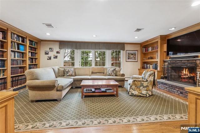 living room featuring crown molding, a fireplace, hardwood / wood-style flooring, and baseboard heating