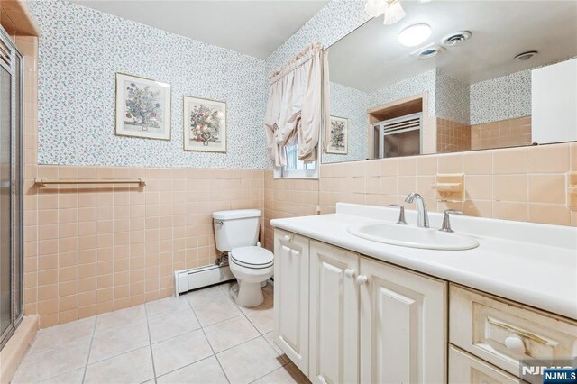 bathroom with baseboard heating, tile walls, vanity, tile patterned floors, and toilet