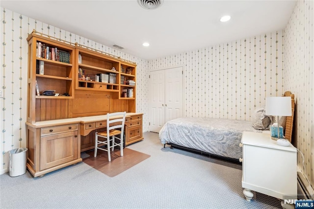 bedroom with built in desk, light colored carpet, and a closet