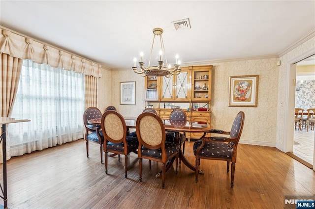 dining room with hardwood / wood-style flooring, ornamental molding, and a chandelier