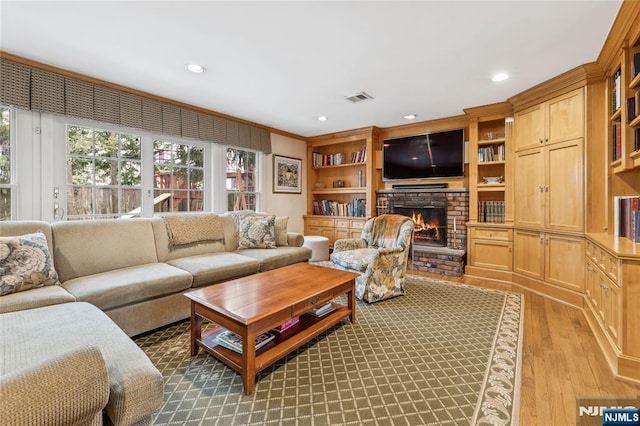 living room featuring a brick fireplace and light hardwood / wood-style floors