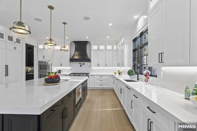 kitchen featuring a center island, sink, pendant lighting, white cabinets, and custom exhaust hood