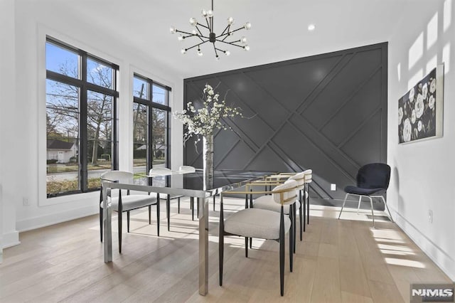 dining area with light wood-type flooring and an inviting chandelier