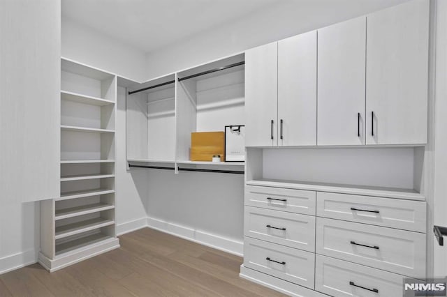 walk in closet with light hardwood / wood-style flooring