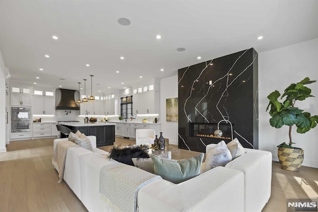 living room featuring a high end fireplace and light hardwood / wood-style floors