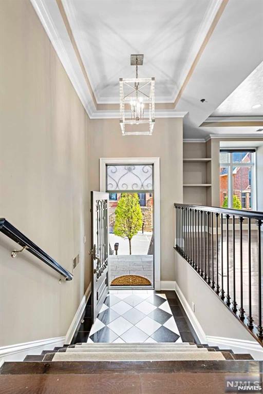 foyer with an inviting chandelier and ornamental molding