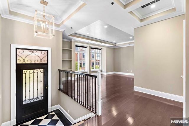 foyer entrance with crown molding, dark hardwood / wood-style flooring, and a notable chandelier