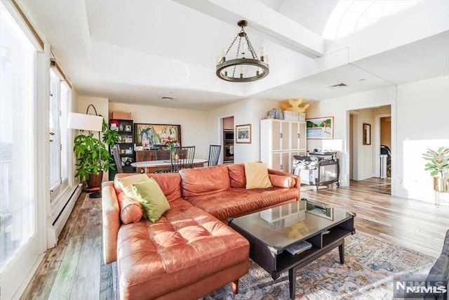 living room featuring a high ceiling, an inviting chandelier, a baseboard radiator, and light hardwood / wood-style flooring