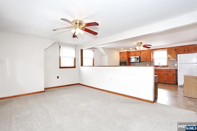 kitchen featuring ceiling fan, white fridge, tasteful backsplash, and light colored carpet