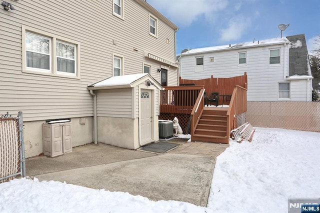 snow covered back of property featuring central AC and a wooden deck