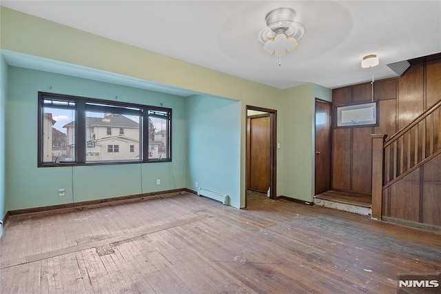 empty room with hardwood / wood-style flooring, baseboard heating, and ceiling fan