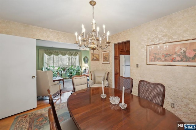 dining room with light wood-style flooring and a notable chandelier