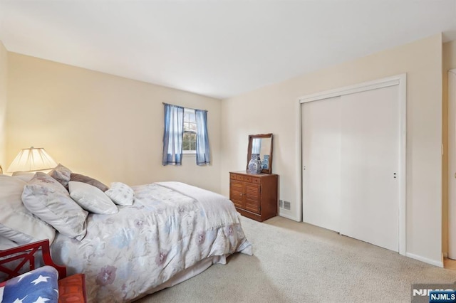 bedroom featuring a closet, light carpet, and visible vents