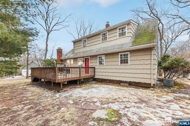 view of front of house featuring roof with shingles, a chimney, a wooden deck, and central AC unit