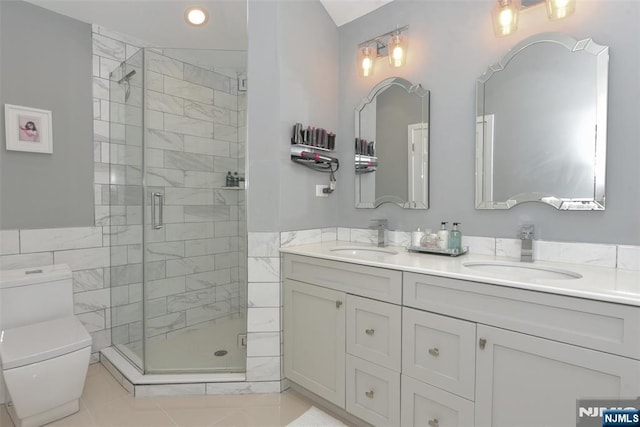 full bathroom with toilet, a shower stall, double vanity, and a sink