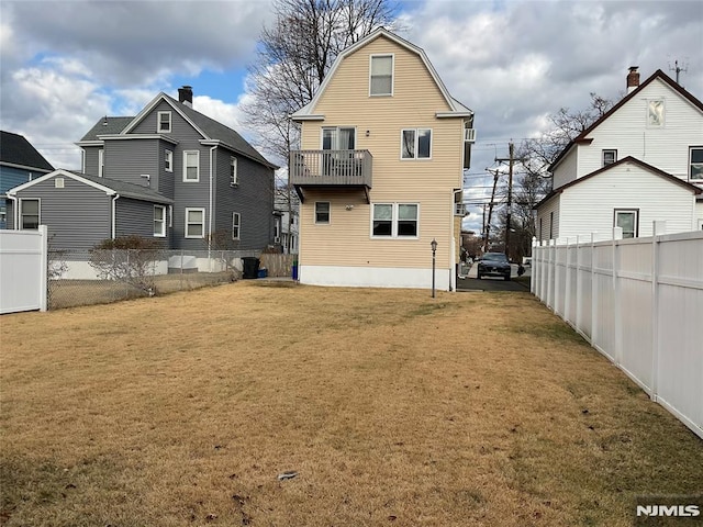 back of house with a yard and a balcony