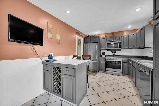 kitchen featuring appliances with stainless steel finishes, light tile patterned floors, gray cabinetry, and sink