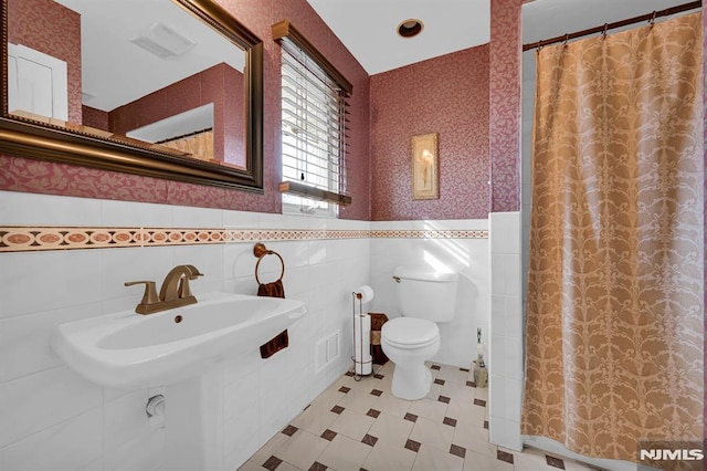 bathroom with toilet, walk in shower, and tile walls