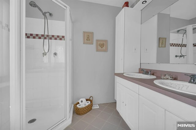 bathroom featuring tile patterned flooring, vanity, and walk in shower