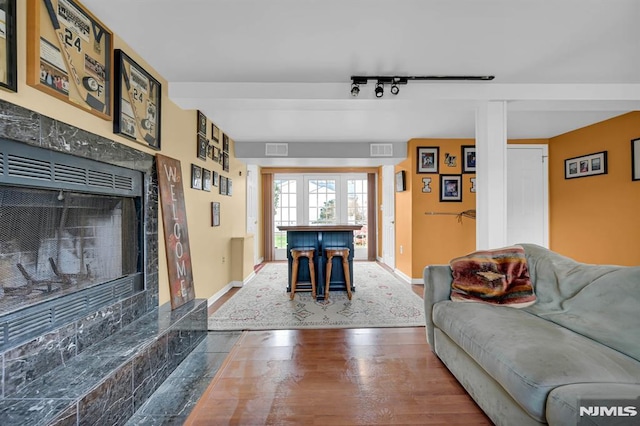 living room featuring a fireplace, hardwood / wood-style floors, indoor bar, and track lighting