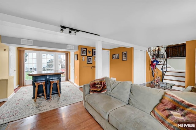 living room with light hardwood / wood-style floors, rail lighting, and bar