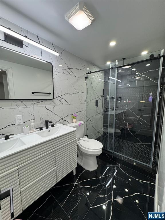 bathroom featuring vanity, a shower with shower door, and toilet