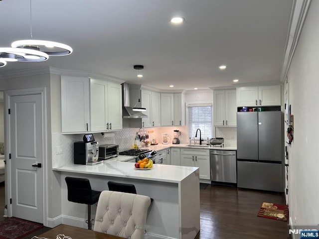 kitchen with pendant lighting, sink, white cabinetry, stainless steel appliances, and kitchen peninsula